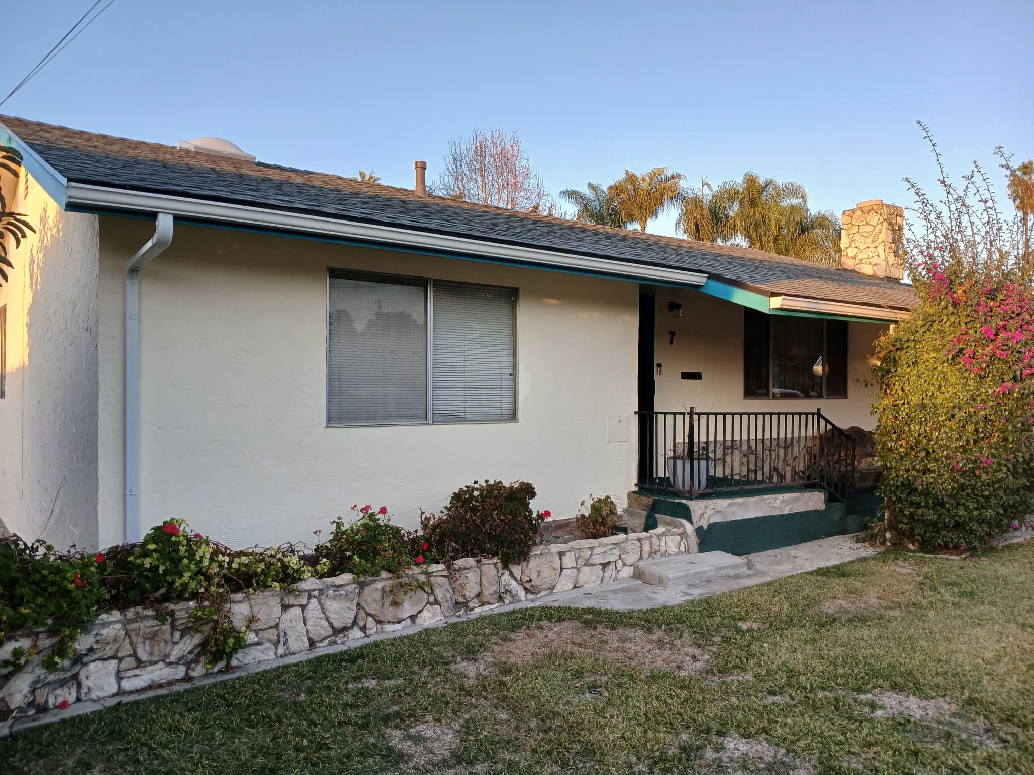 White stucco home with palm trees and fresh gutters in Red Bluff