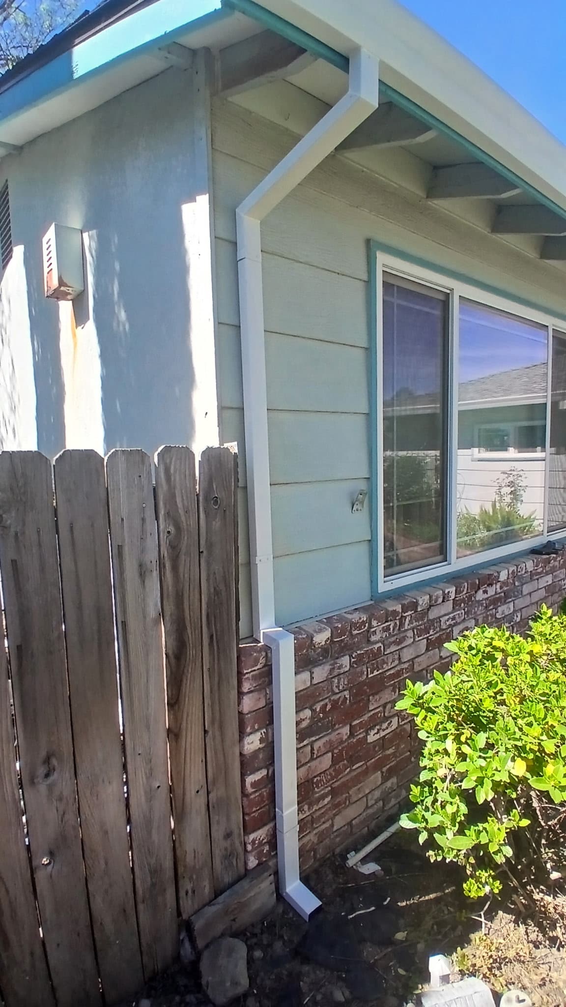 White seamless gutter and downspout detail on a teal cottage in Palo Cedro